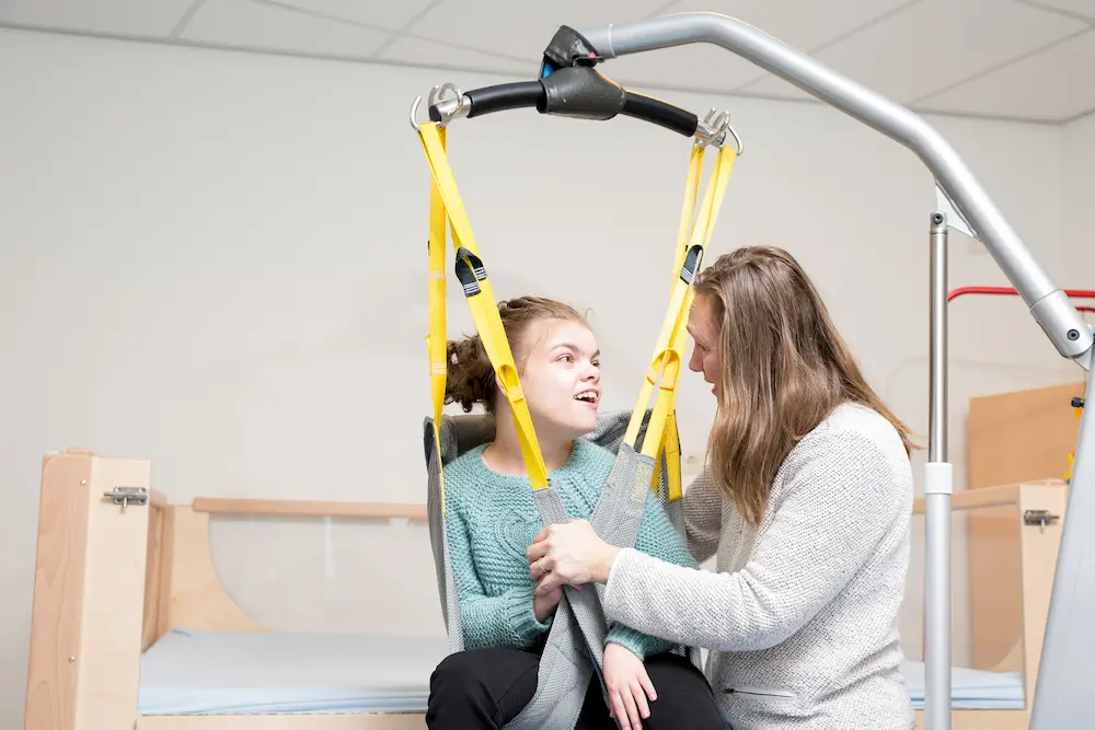 Disability a disabled child being cared for / Disability a disabled child being cared for by a special needs carer using specialist lifting equipment