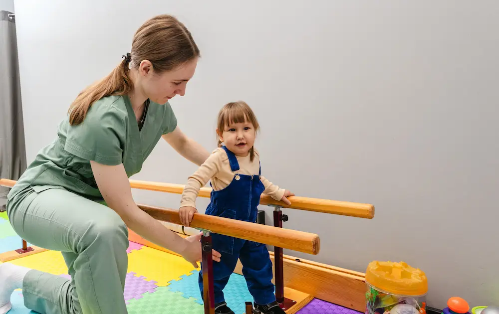 Little female child is engaging in physical therapy, assisted by a caregiver