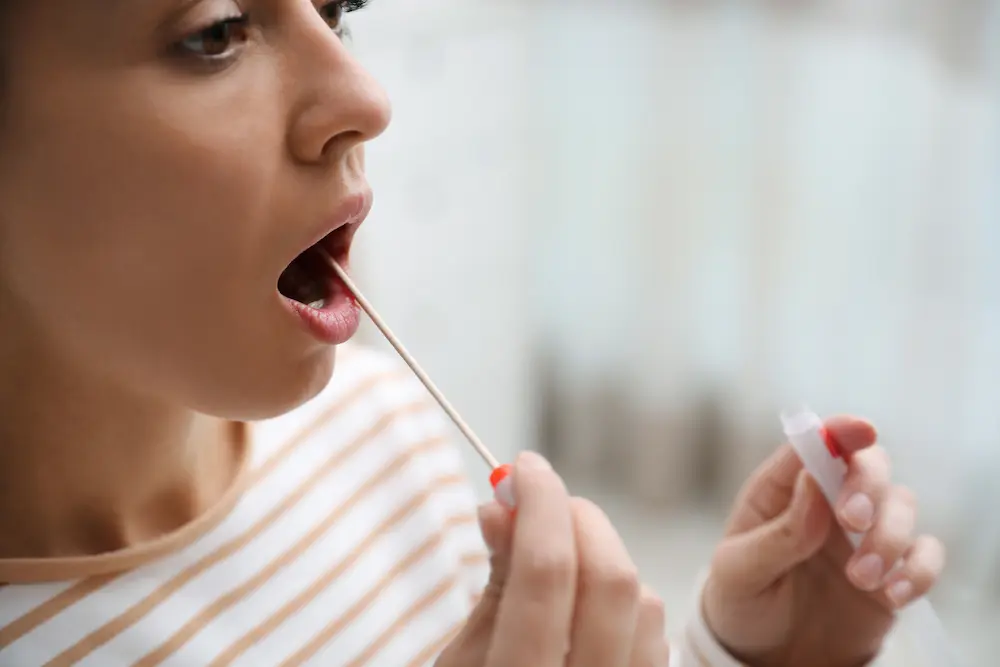 Woman taking sample for DNA test indoors, closeup
