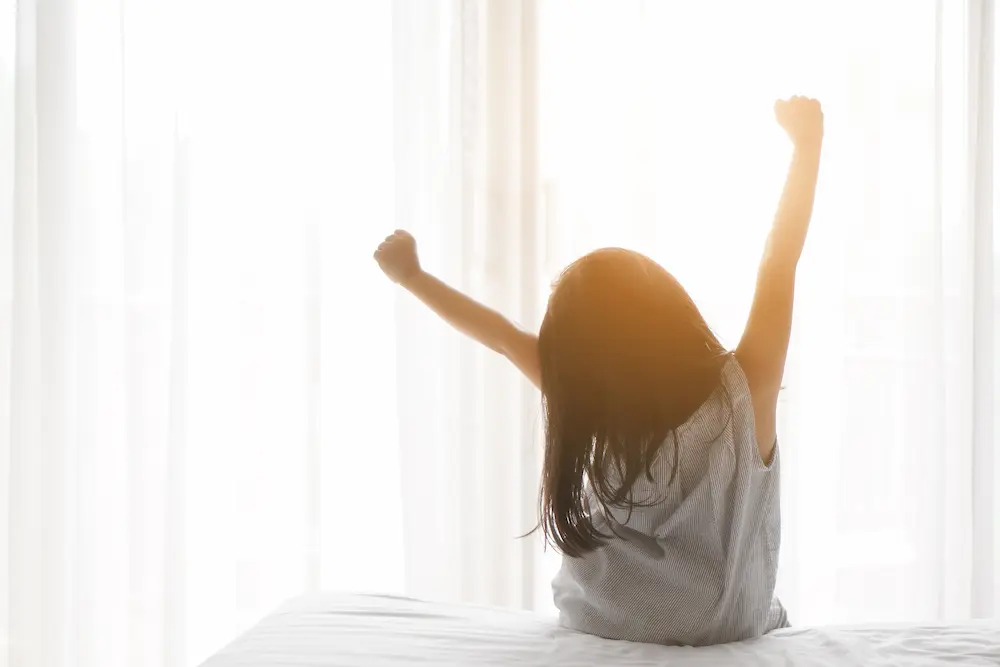 kid girl wake up or woke up with stretch oneself after refreshing sleep in morning on white bed